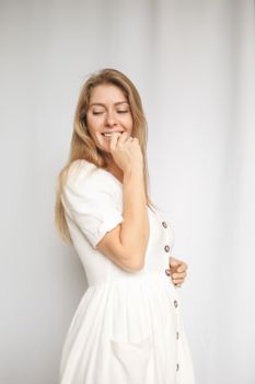 一位开朗的女子穿着白色连衣裙，在干净的白色背景下微笑着摆姿势