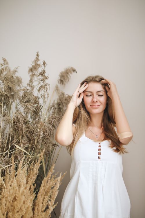 Free A serene woman with a prosthetic arm stands by dried plants, embodying beauty and resilience. Stock Photo