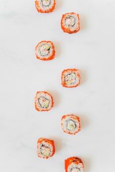 Vertical shot of California sushi rolls with crab, cucumber, and avocado on white.