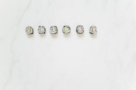 Black sesame seed sushi rolls aligned on a marble white background.