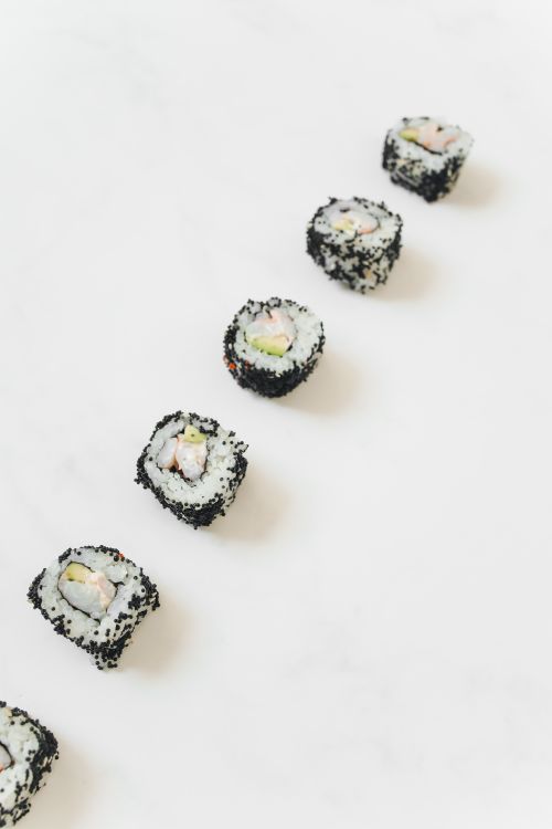 Free A row of sushi rolls creatively arranged on a clean, white surface. Stock Photo