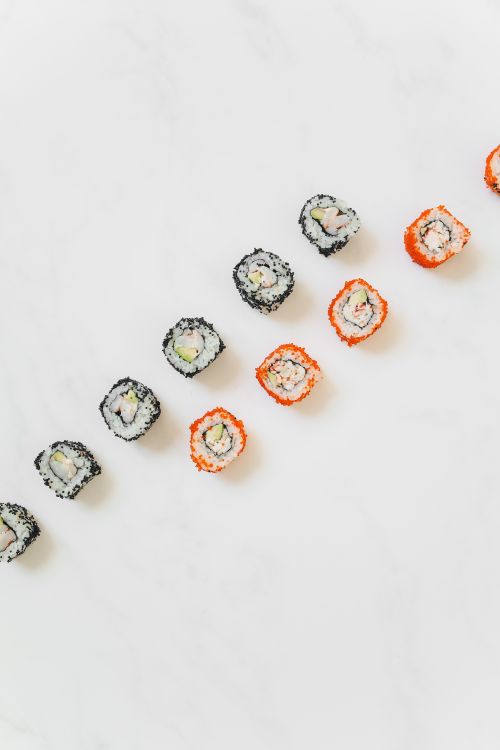 Free Colorful sushi rolls arranged diagonally on a white background in minimalist style. Stock Photo