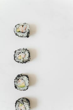 Vertical shot of sushi rolls on a white surface, showcasing minimalistic food presentation.