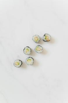 Six sushi rolls on a white marble background, showcasing simplicity and elegance.