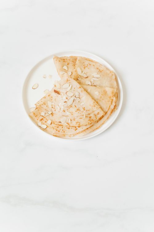 Free Delicious crepes topped with sliced almonds on a minimalist white plate. Stock Photo