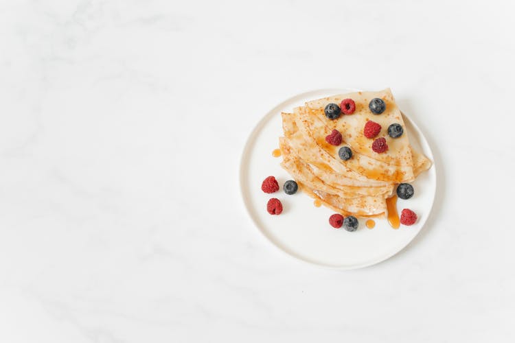 Homemade Crepes With Berries On White Plate