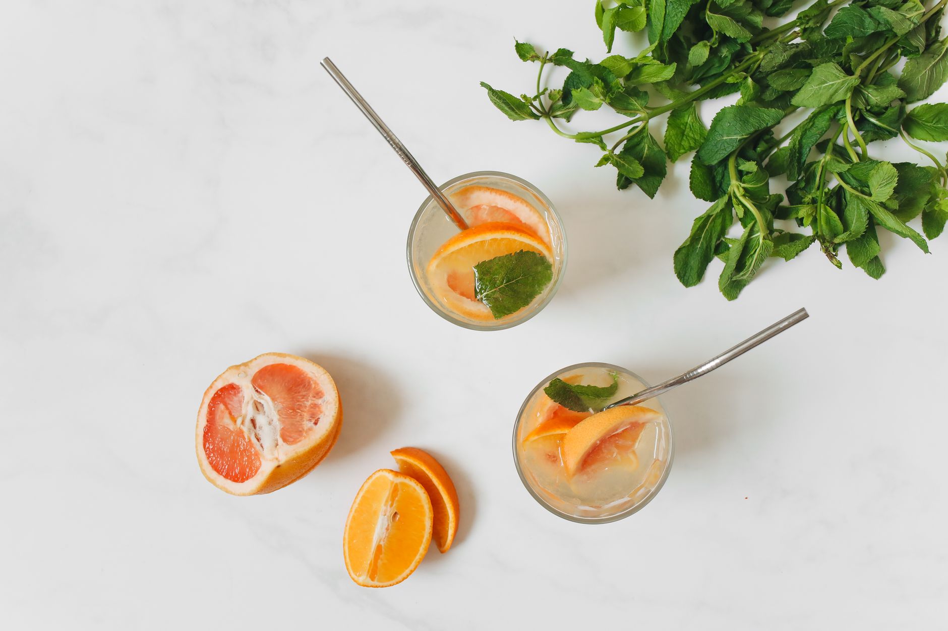 Top view of citrus and mint infused drinks with grapefruit and orange slices, offering a refreshing and healthy refreshment option.