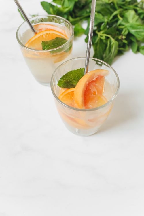 Free Two refreshing citrus beverages with mint and orange slices in clear glasses, perfect for summer. Stock Photo