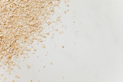Free Close-up of scattered oatmeal on a clean white background, perfect for food-related themes. Stock Photo