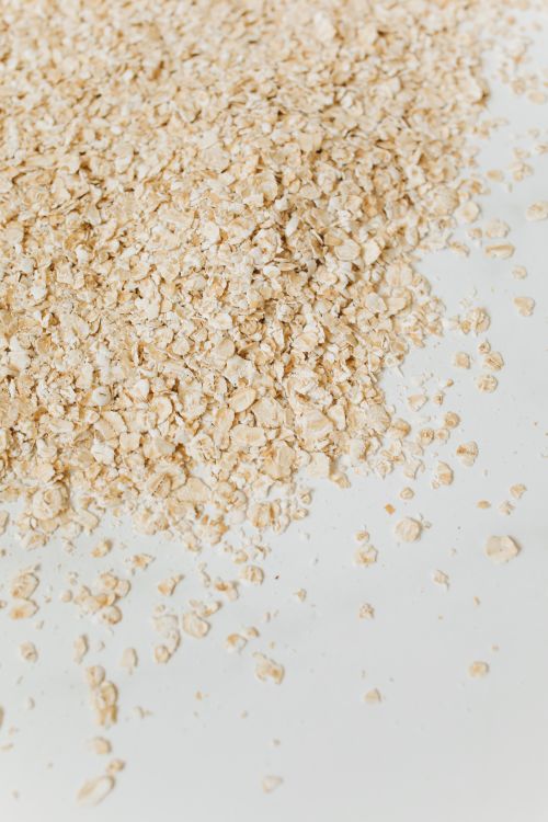 Free Close-up of raw oats scattered on a white surface, highlighting texture. Stock Photo