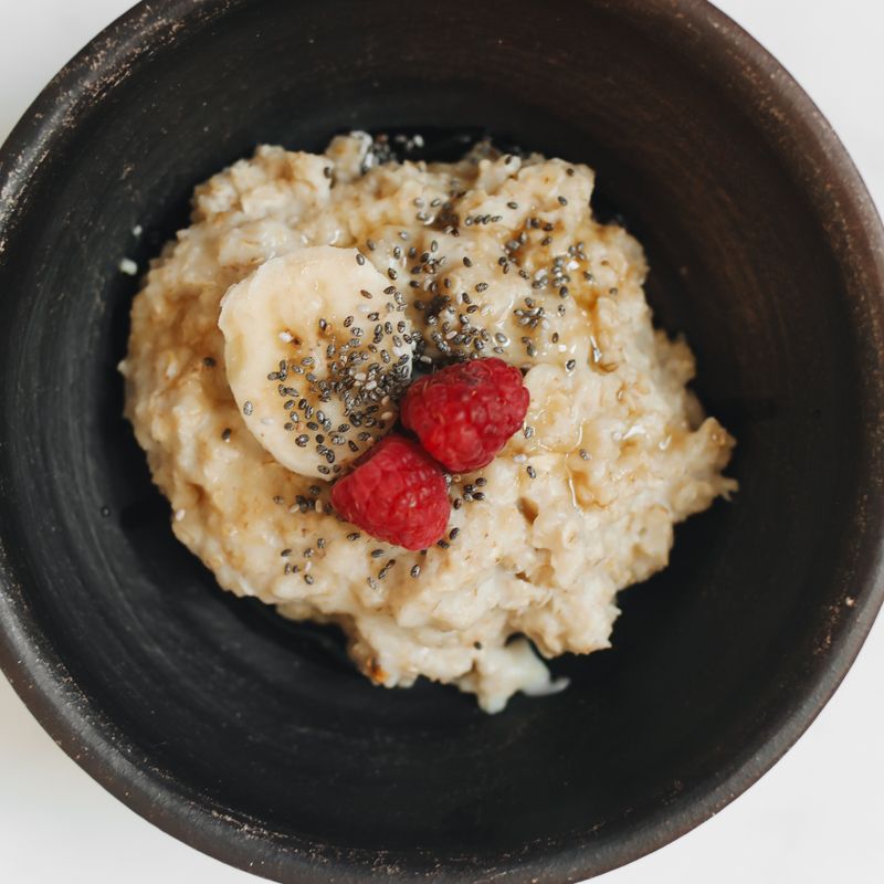 Oatmeal topped with banana slices, raspberries and chia seeds