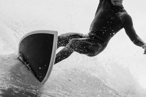 Grayscale Photo of a Man Surfboarding