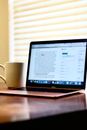 Black Laptop Computer Turned on Beside White Ceramic Mug