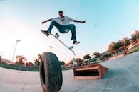 Young tattooed skater jumping above tire