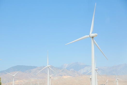 Wind turbines in a mountainous landscape under a clear blue sky. Ideal for renewable energy themes.