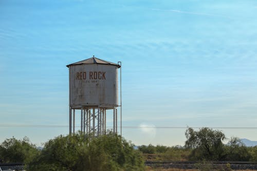 Water tower among greenery against blue sky