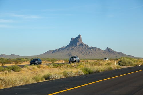 Modern cars riding on paved road near mountain valley