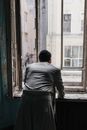 一名男子身穿复古内饰，向窗外望去，捕捉到一种怀旧和沉思的感觉