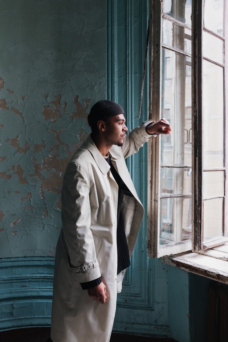 Man In Gray Suit Jacket And Black Knit Cap Standing Beside Blue And White Painted Wall