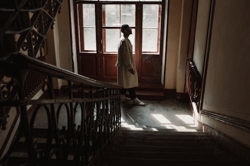 Man in Brown Coat Standing on Hallway