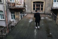 一名男子在复古的城市庭院中，探索着古老而饱经风霜的屋顶