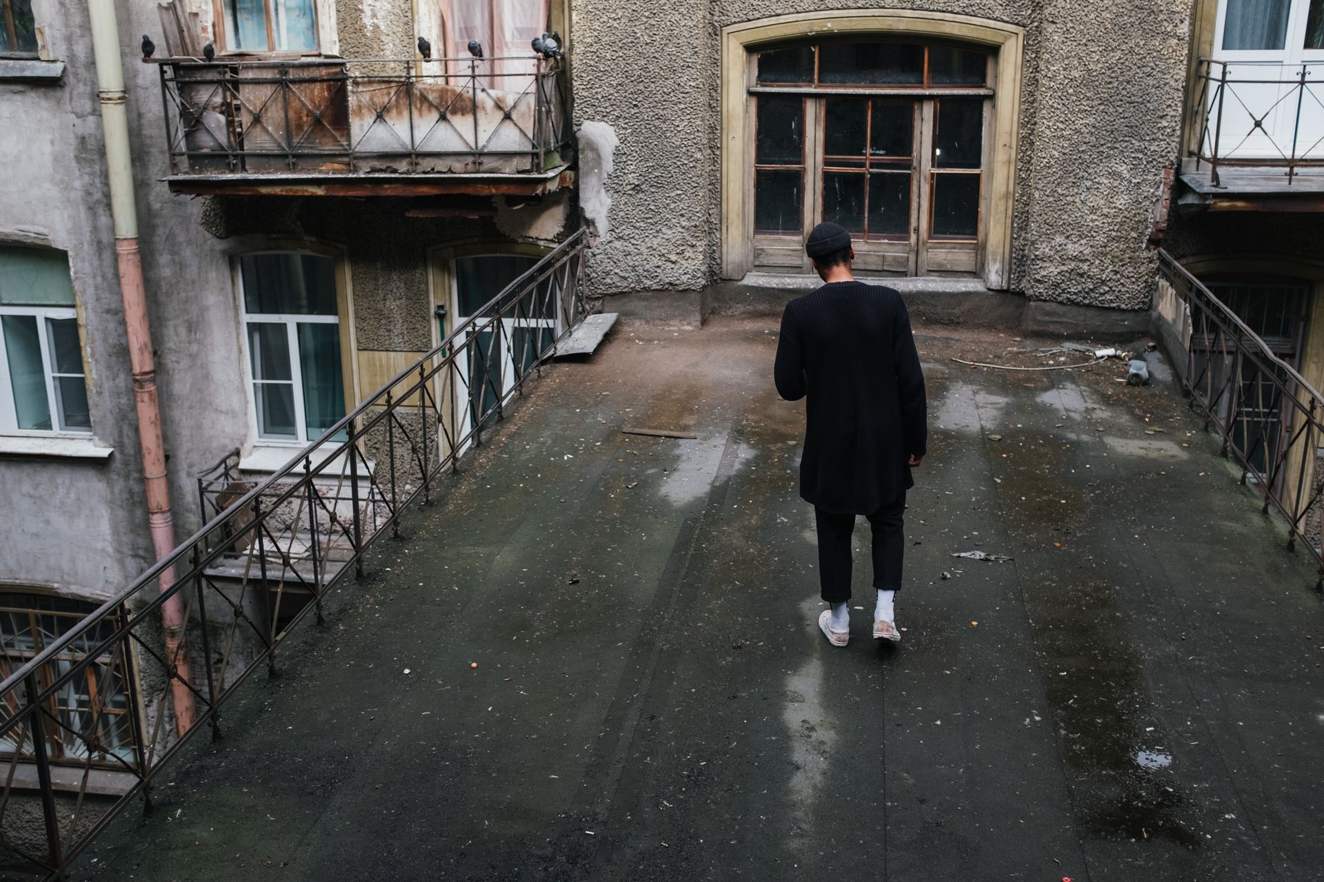 Man exploring an aged, weathered rooftop in a vintage urban courtyard setting.