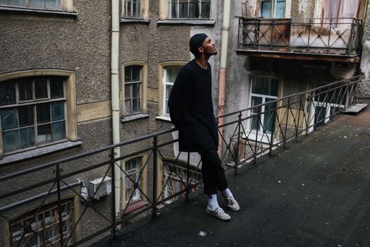 一名男子站在城区一栋复古建筑的破旧阳台上