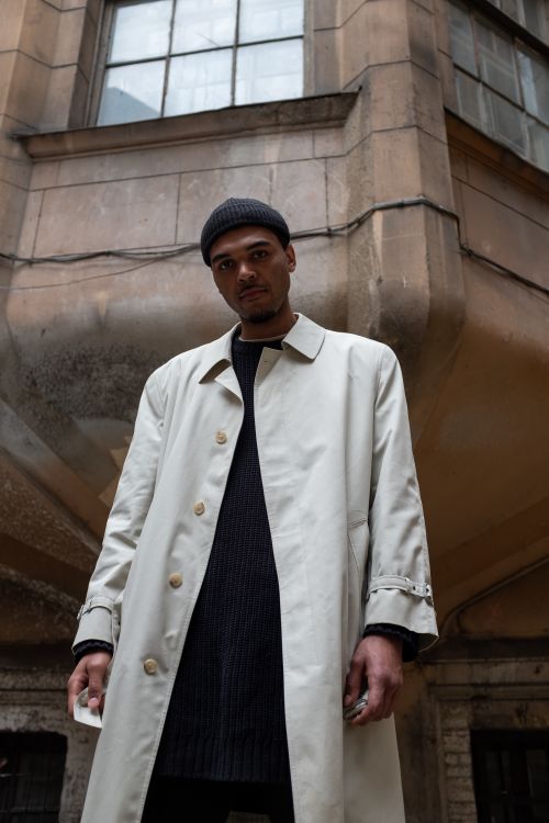 Free Stylish man in beige coat posing in an old architectural courtyard. Stock Photo