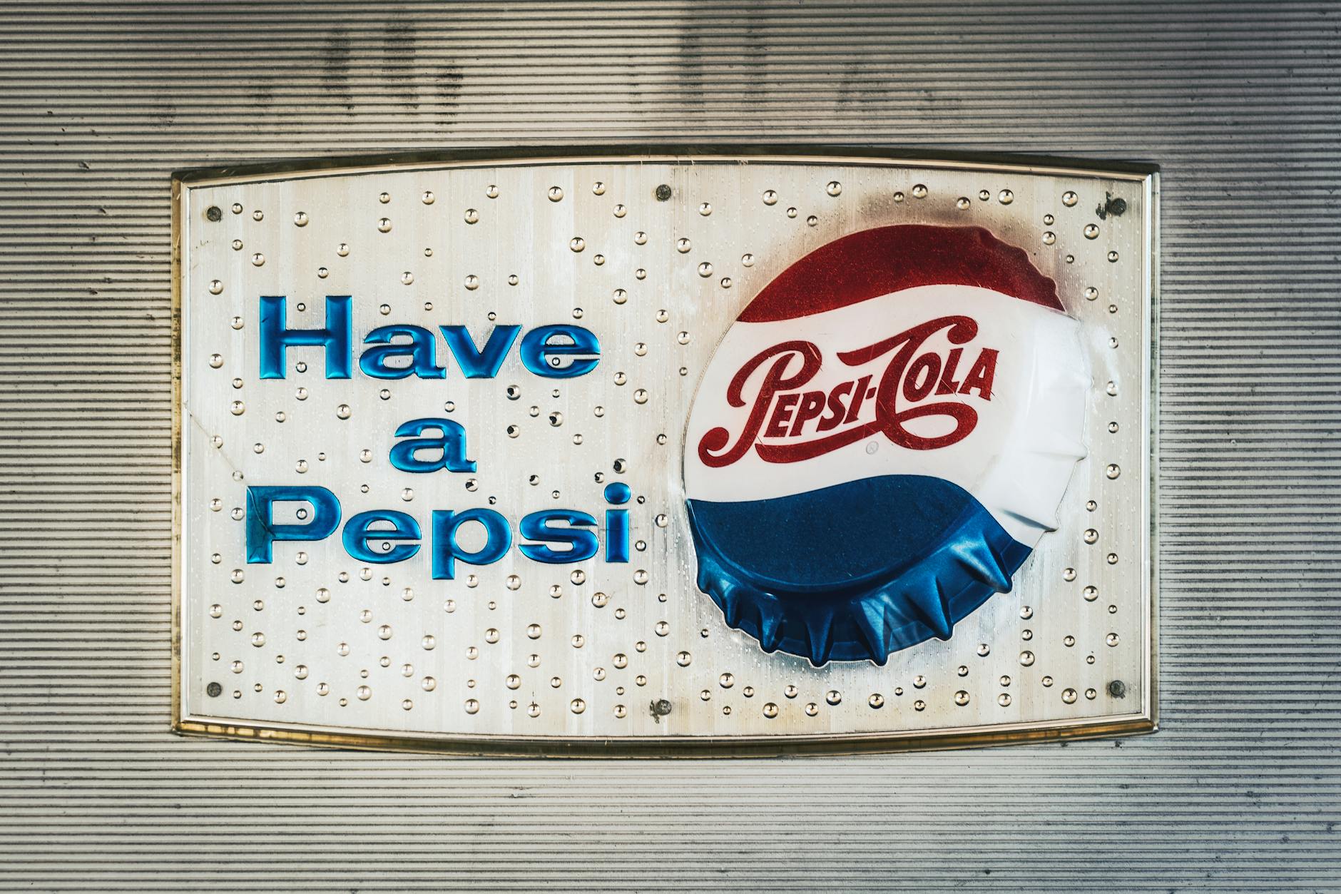 Retro Pepsi Cola sign featuring classic logo and bottle cap design.