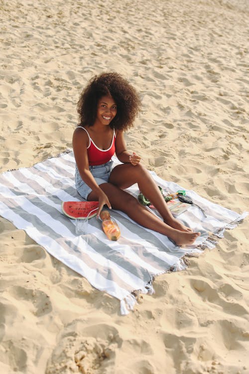 Free Woman Wearing Red Top Sitting on White Sand Stock Photo