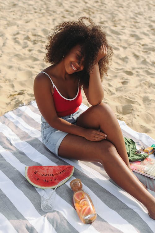 Free Woman Wearing Red Top Sitting on White Sand Stock Photo