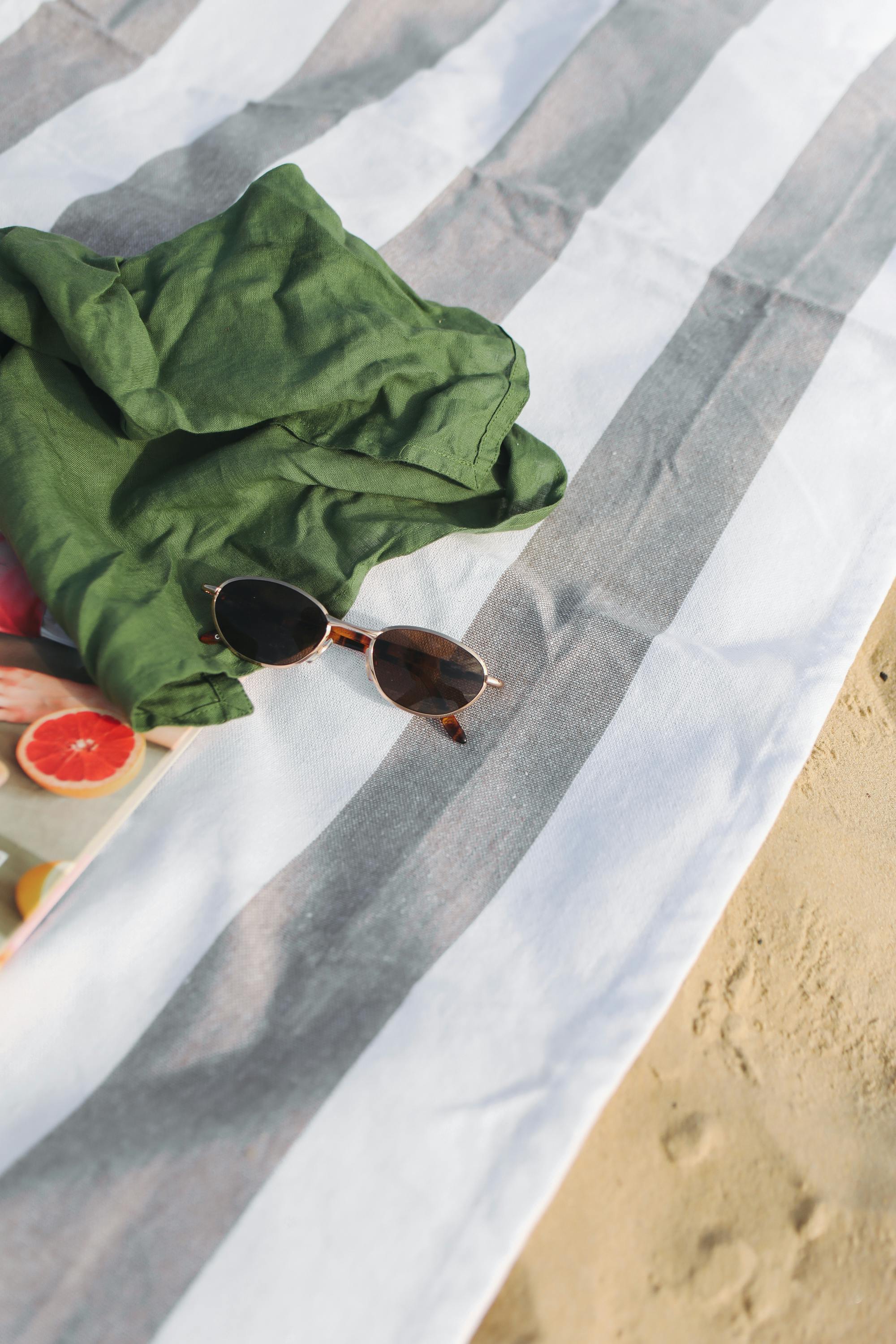 silver framed aviator style sunglasses and shirt on a beach towel