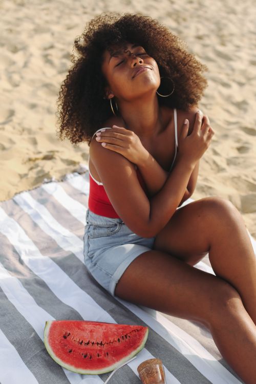 Free Woman enjoying sunbathing on the beach with fresh watermelon. Stock Photo