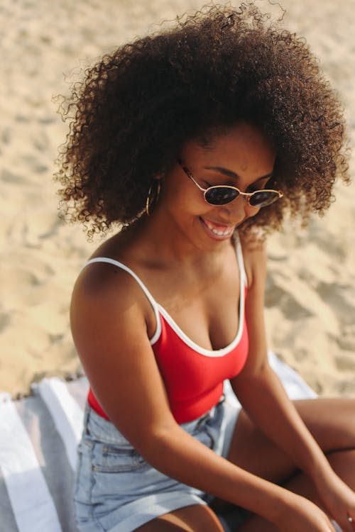 Free Woman in Red and White Spaghetti Strap Top With Sunglasses Sitting on a Beach Towel On Sand Stock Photo