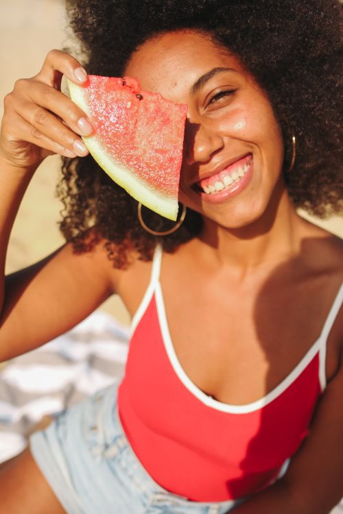 Free Happy woman enjoying summer holding watermelon slice on a sunny beach day. Stock Photo