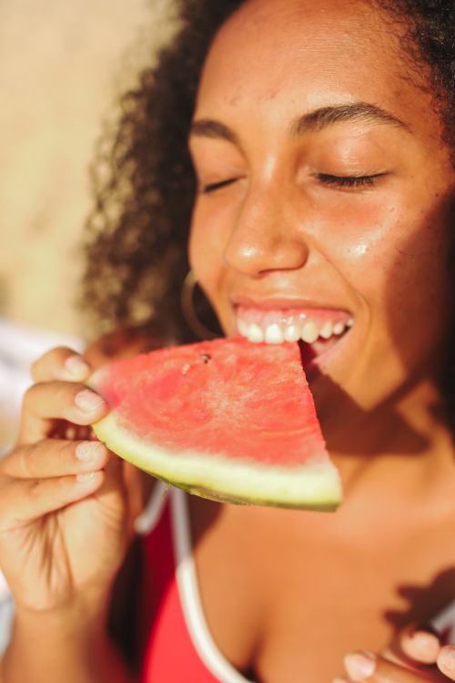 Free Portrait of a woman savoring a watermelon slice, capturing summer joy. Stock Photo