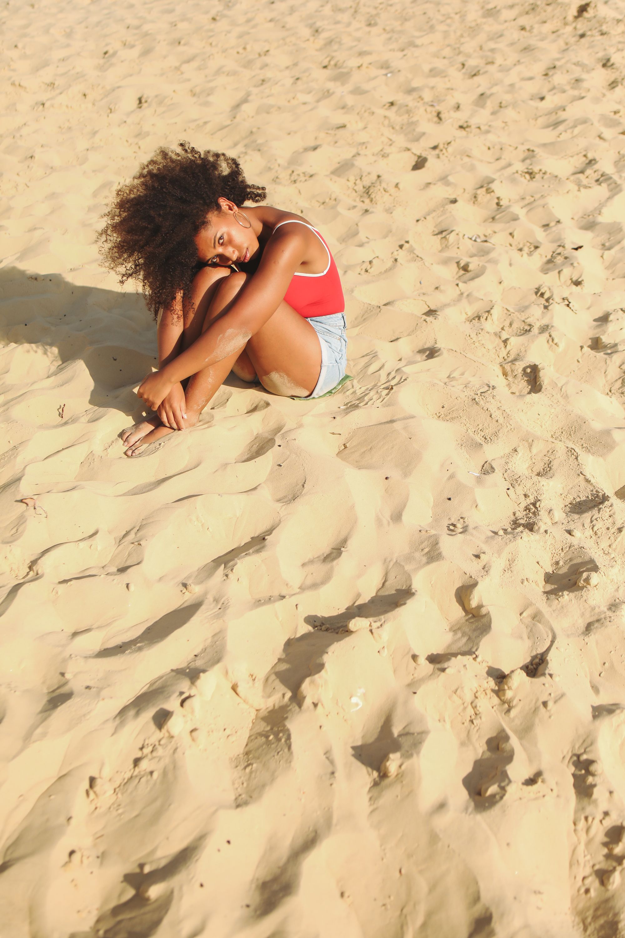 Woman in Red Top Sitting on a White Sand · Free Stock Photo