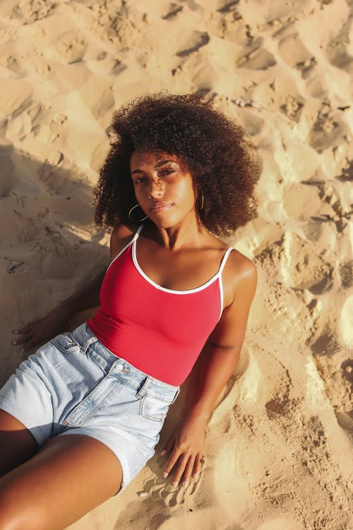 Free Woman Wearing Red Top Sitting on White Sand Stock Photo