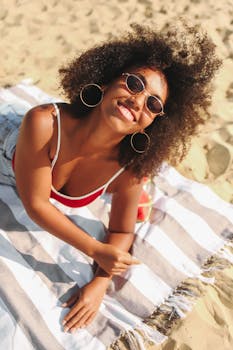 阳光明媚的海滩上，一位快乐的女人躺在条纹毛巾上，笑容灿烂