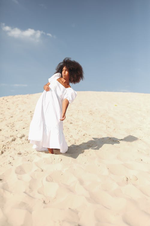 Woman Posing in White Dress Standing on Sand