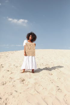 一名黑人妇女站在沙漠中，高举“黑人的命也是命”标语，强调自由与抗议