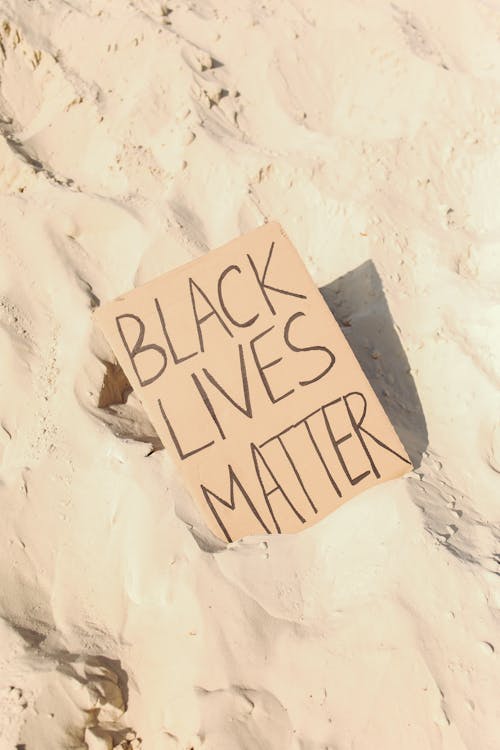 Black Lives Matter Written on Cardboard on Sand