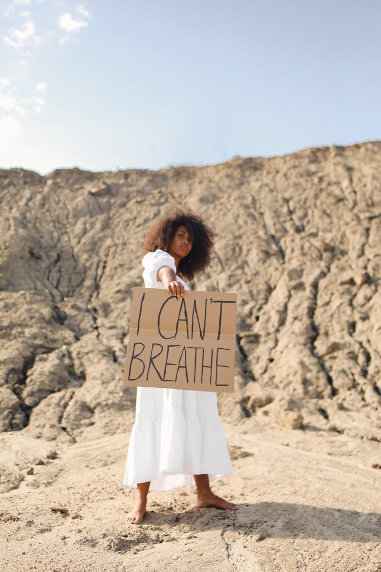 A Woman In White Dress Showing The Message Of The Cardboard She Is Holding