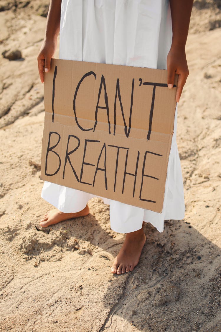 A Person In White Skirt Holding A Cardboard With Message