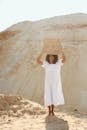 Woman in White Dress Holding Brown Wooden Board