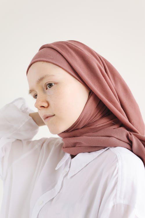 Close-Up Photo of a Young Woman Posing in White Long Sleeve Shirt and Brown Hijab