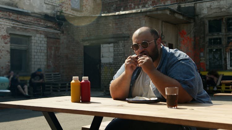 Man At The Wooden Table Eating Hamburger 