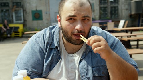Man in Blue Denim Button Up Shirt Eating Food