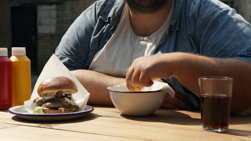 Person Holding French Fries From Ceramic Bowl 