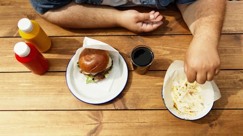 Person Holding French Fries From Ceramic Bowl 